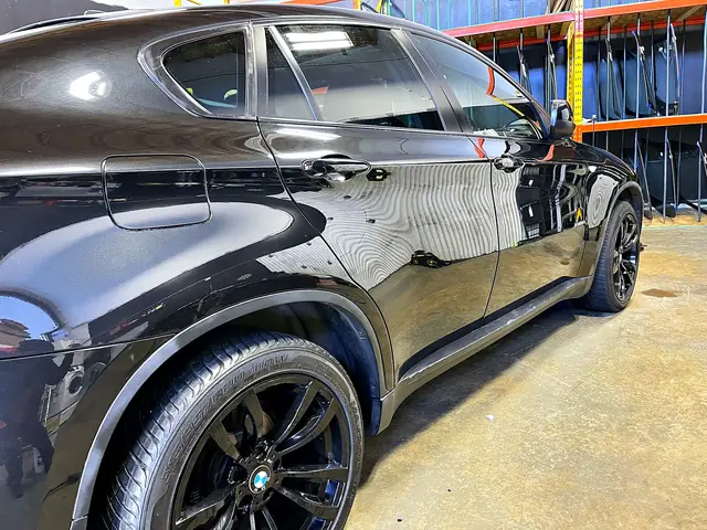 Close view of the glossy dark paint on the side of a BMW X6