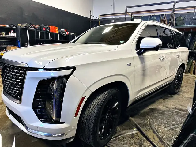 White Cadillac Escalade, front three-quarter view in the shop