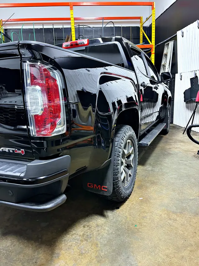 Black GMC Canyon AT4 pickup with a deep, mirror-like gloss after polishing