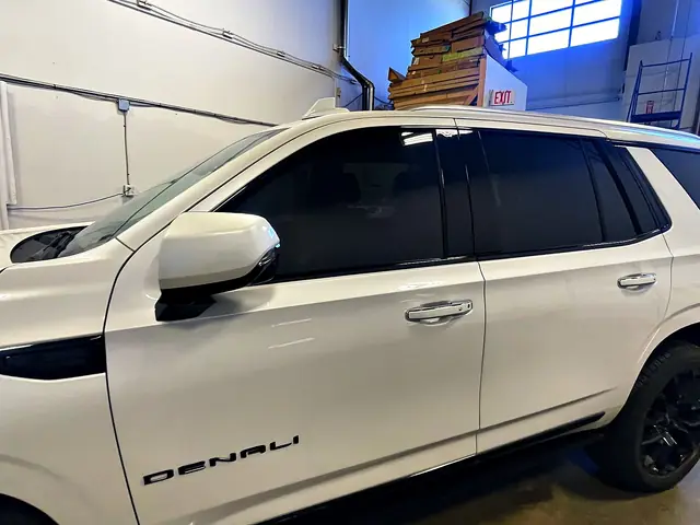 Close view of the front side windows on a white GMC Yukon Denali after tinting