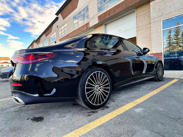 Black Mercedes-Benz E-Class, rear three-quarter view in front of the shop